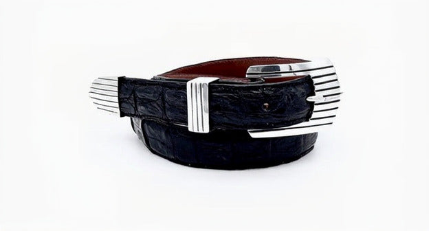 A sterling silver belt buckle with a southwestern design, featuring a buckle, keeper, and tip, displayed on a black caiman belt strap.